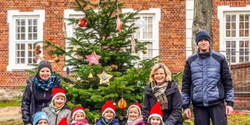 Kindergartenkinder schmücken Weihnachtsbaum